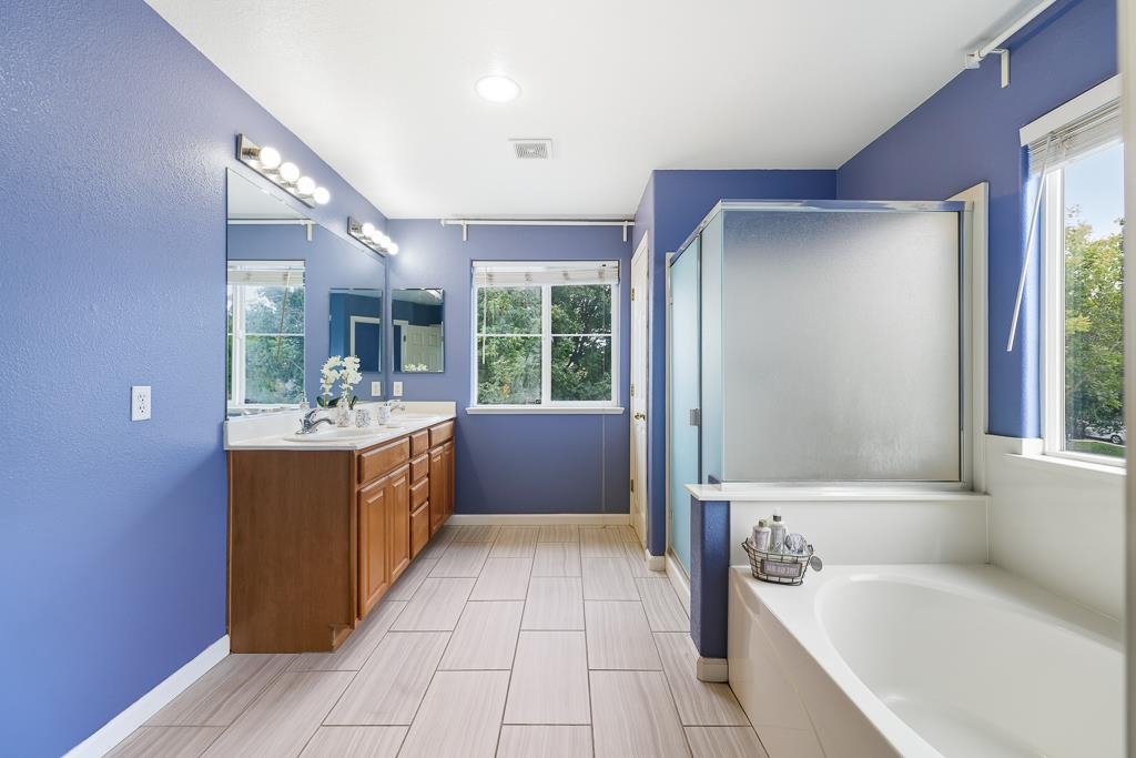1413 Angus Street Patterson, CA 95363 - Photo 12 of 60 a large bathroom with a tub a sink a mirror and a shower
