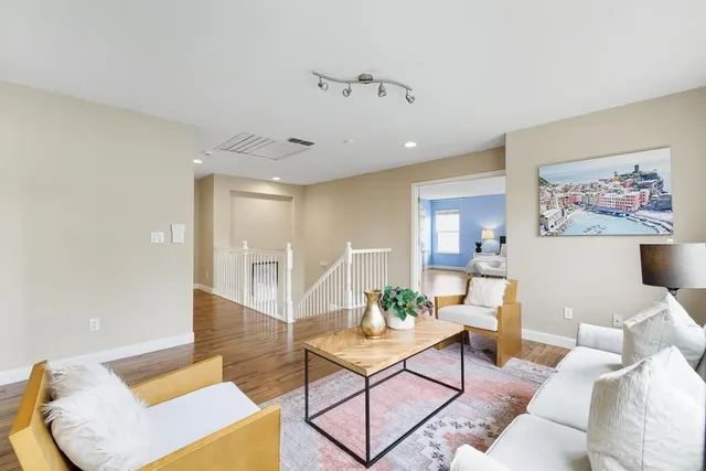a bedroom with a large bed a potted plant and a wooden floor