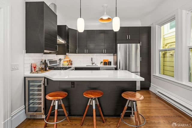 a kitchen with stainless steel appliances a dining table chairs and a large window