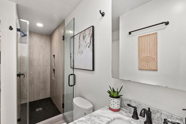 a bathroom with a granite countertop sink a toilet and a shower