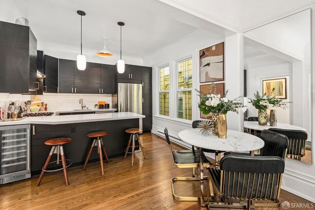 a kitchen with stainless steel appliances kitchen island granite countertop a dining table chairs and a refrigerator