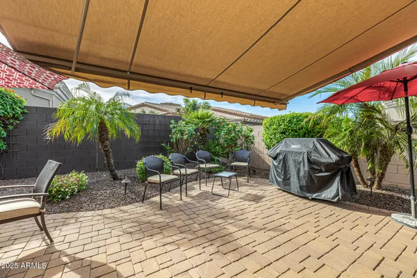 a view of a patio with table and chairs under an umbrella with a small yard
