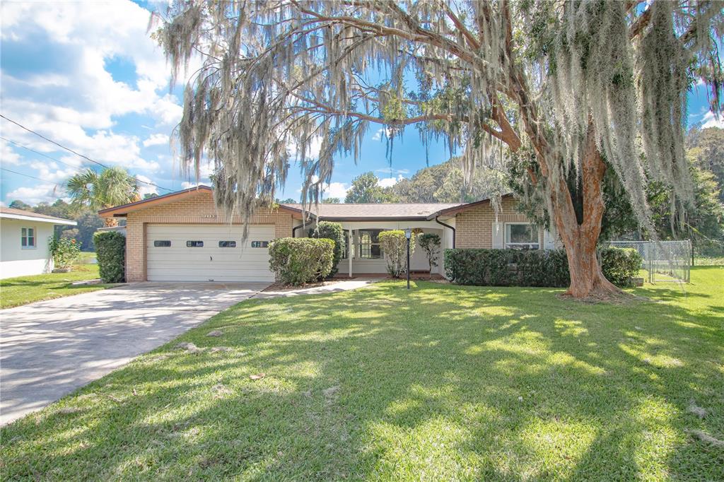 12190 Maple Street Dunnellon, FL 34432 - Photo 1 of 1 a front view of a house with a garden and trees