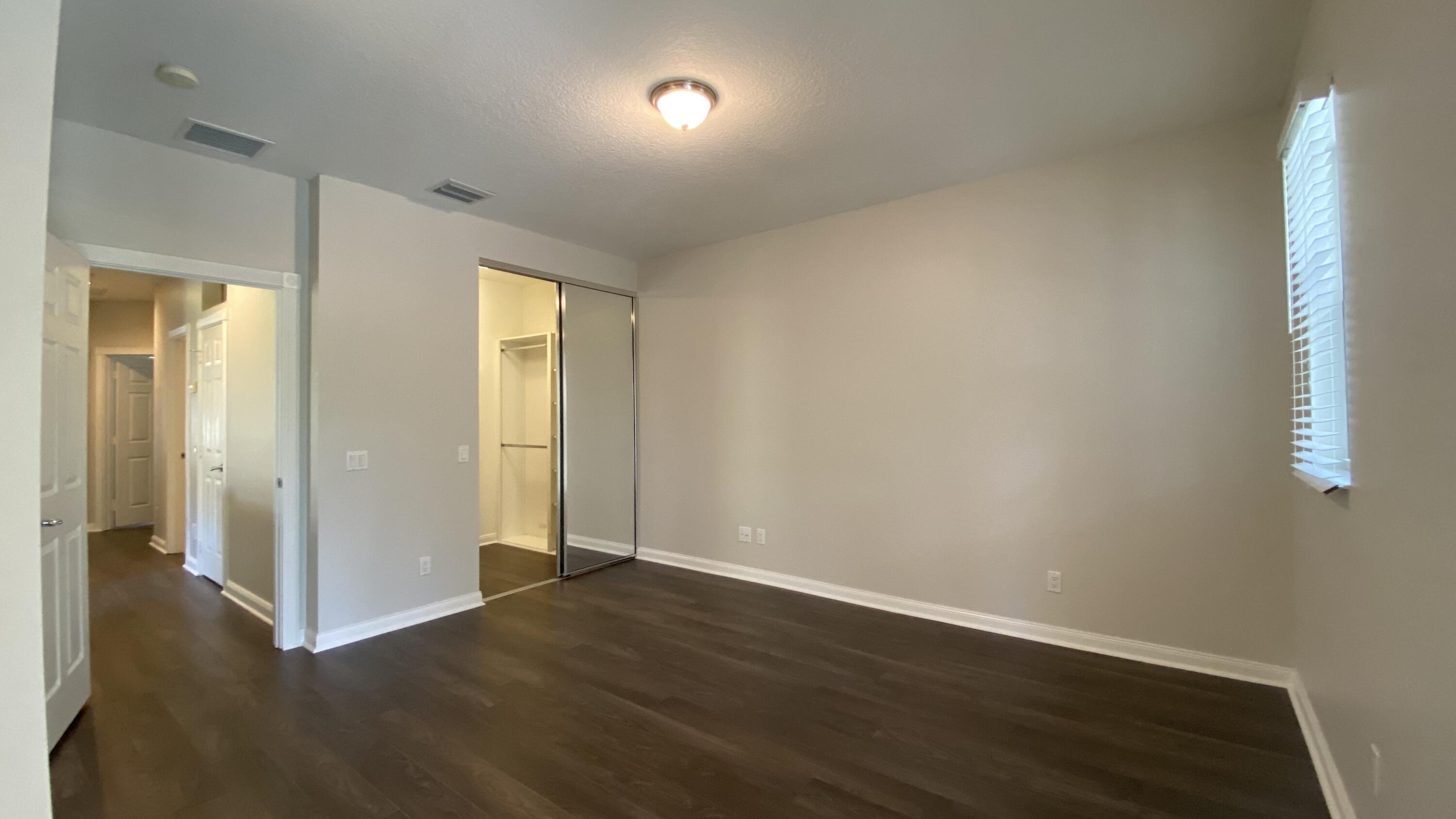 3200 West Community Drive Jupiter, FL 33458 - Photo 18 of 31 an empty room with wooden floor and windows