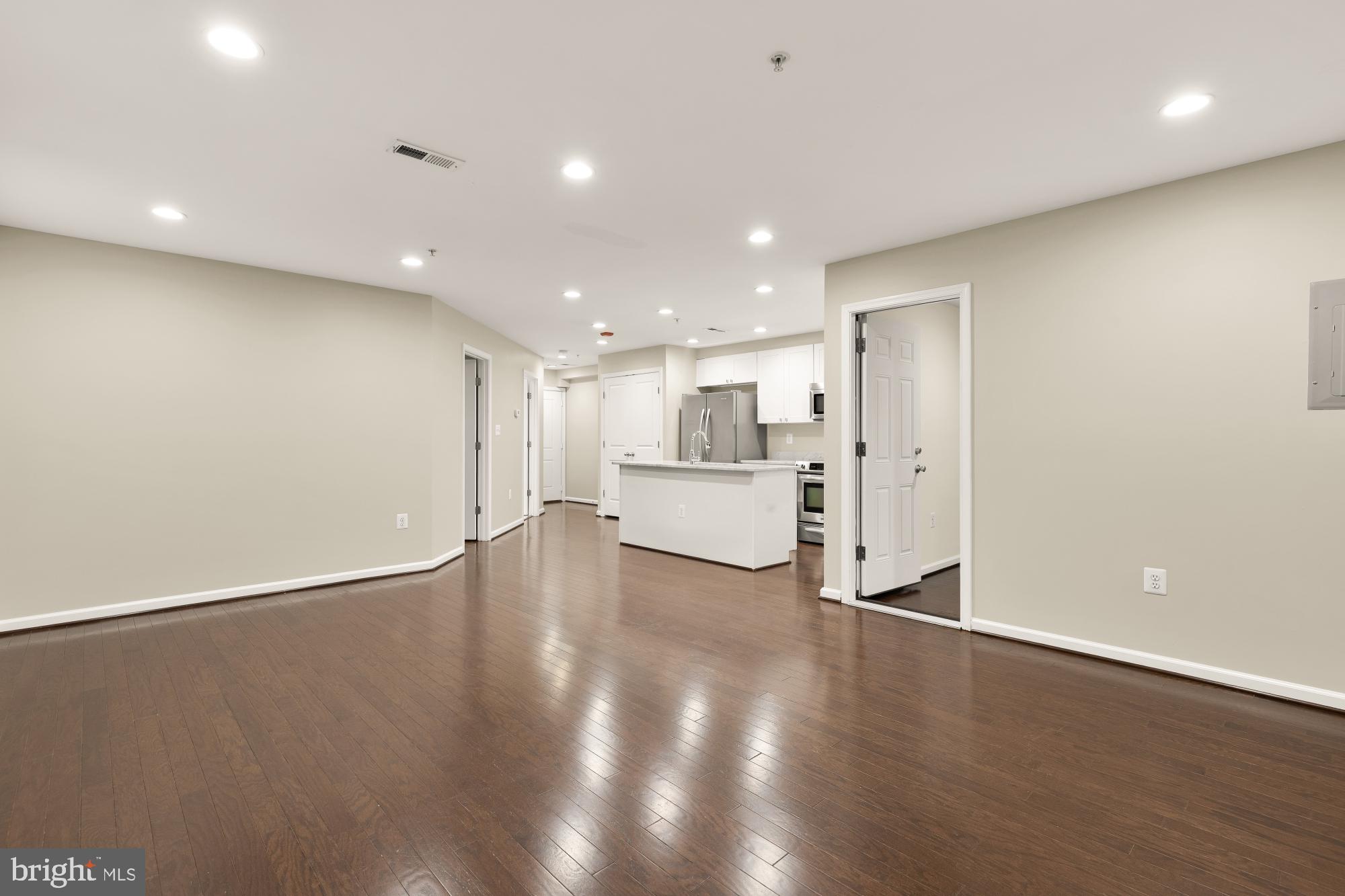 1845 Kalorama Road Northwest, Unit 1 Washington, DC 20009 - Photo 17 of 39 a view of an empty room with wooden floor and a kitchen