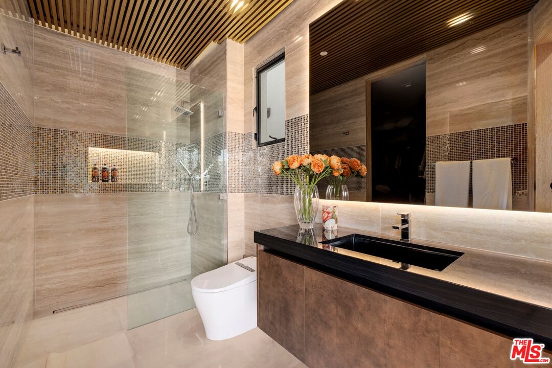 976 Bel Air Road Los Angeles, CA 90077 - Photo 15 of 23 a bathroom with a granite countertop sink a toilet and shower