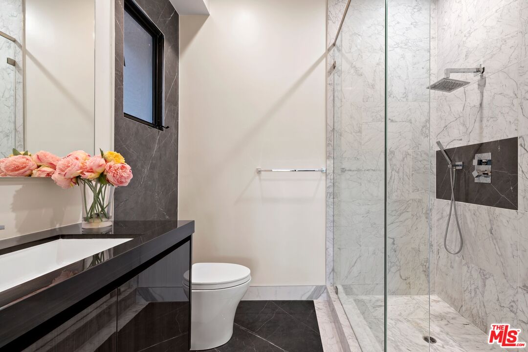 976 Bel Air Road Los Angeles, CA 90077 - Photo 17 of 23 a bathroom with a granite countertop sink a toilet and shower
