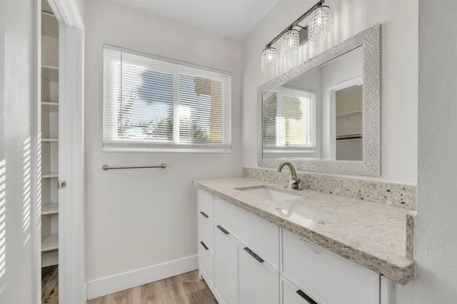 a bathroom with a granite countertop sink and a window