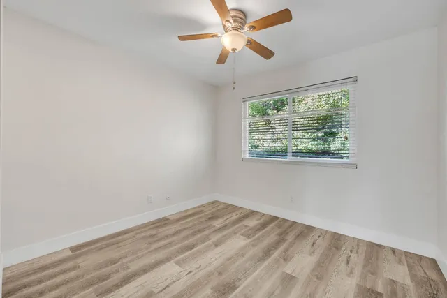 an empty room with a window and a fan