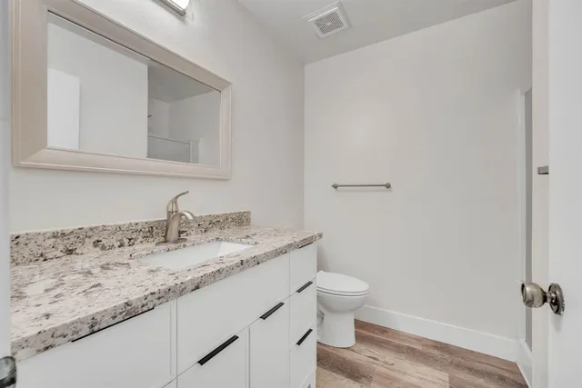 a bathroom with a granite countertop sink a toilet and a mirror