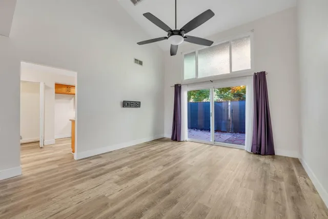 an empty room with wooden floor a ceiling fan and windows
