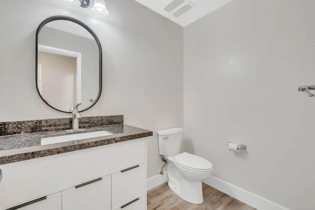 a bathroom with a granite countertop toilet a sink and a mirror
