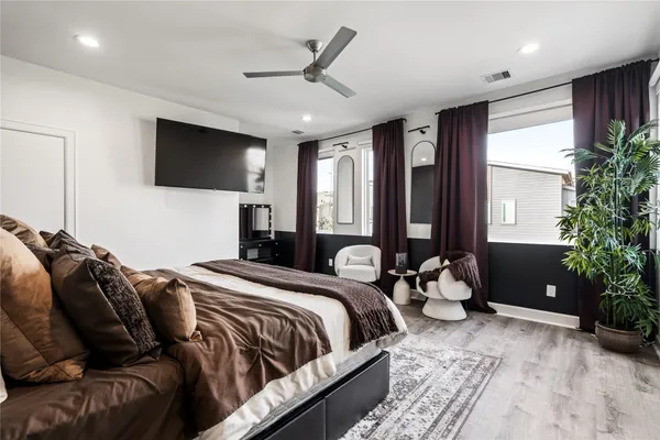 a bedroom with a bed a flat screen tv and a large window