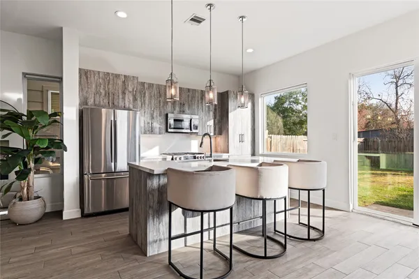 a kitchen with stainless steel appliances granite countertop a refrigerator a sink a stove and chairs