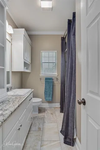 a bathroom with a granite countertop sink a toilet and shower