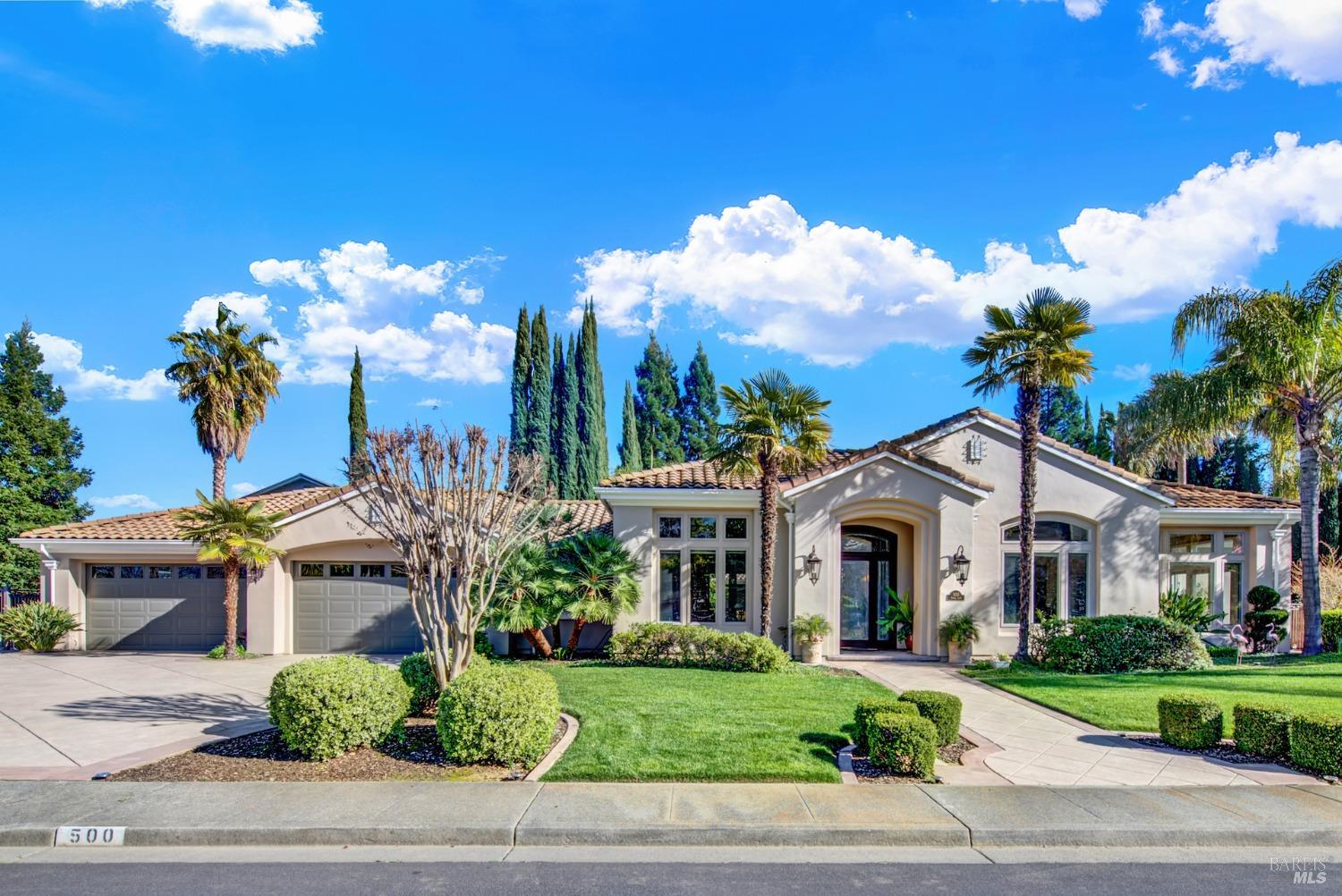 a view of a white house with a yard and potted plants