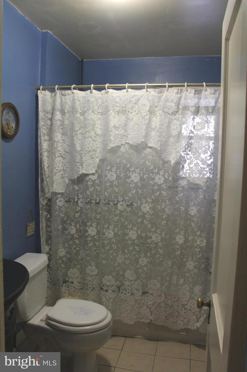 3015 Dunleer Road Baltimore, MD 21222 - Photo 13 of 18 a white toilet sitting next to a shower curtain
