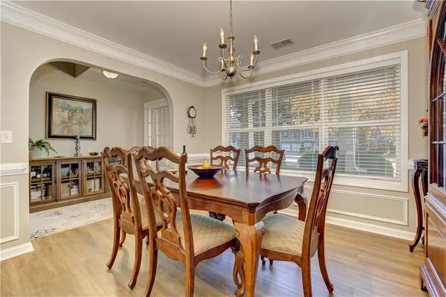 a kitchen with stainless steel appliances granite countertop wooden cabinets a sink a stove a dining table and chairs