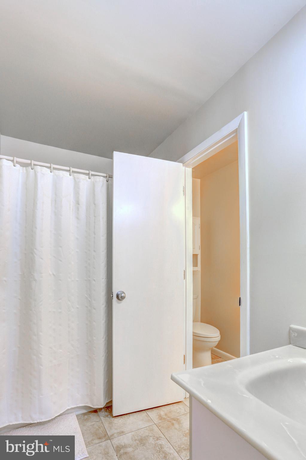 8018 Valley Manor Road, Unit 1A Owings Mills, MD 21117 - Photo 14 of 24 a bathroom with a shower curtain and sink