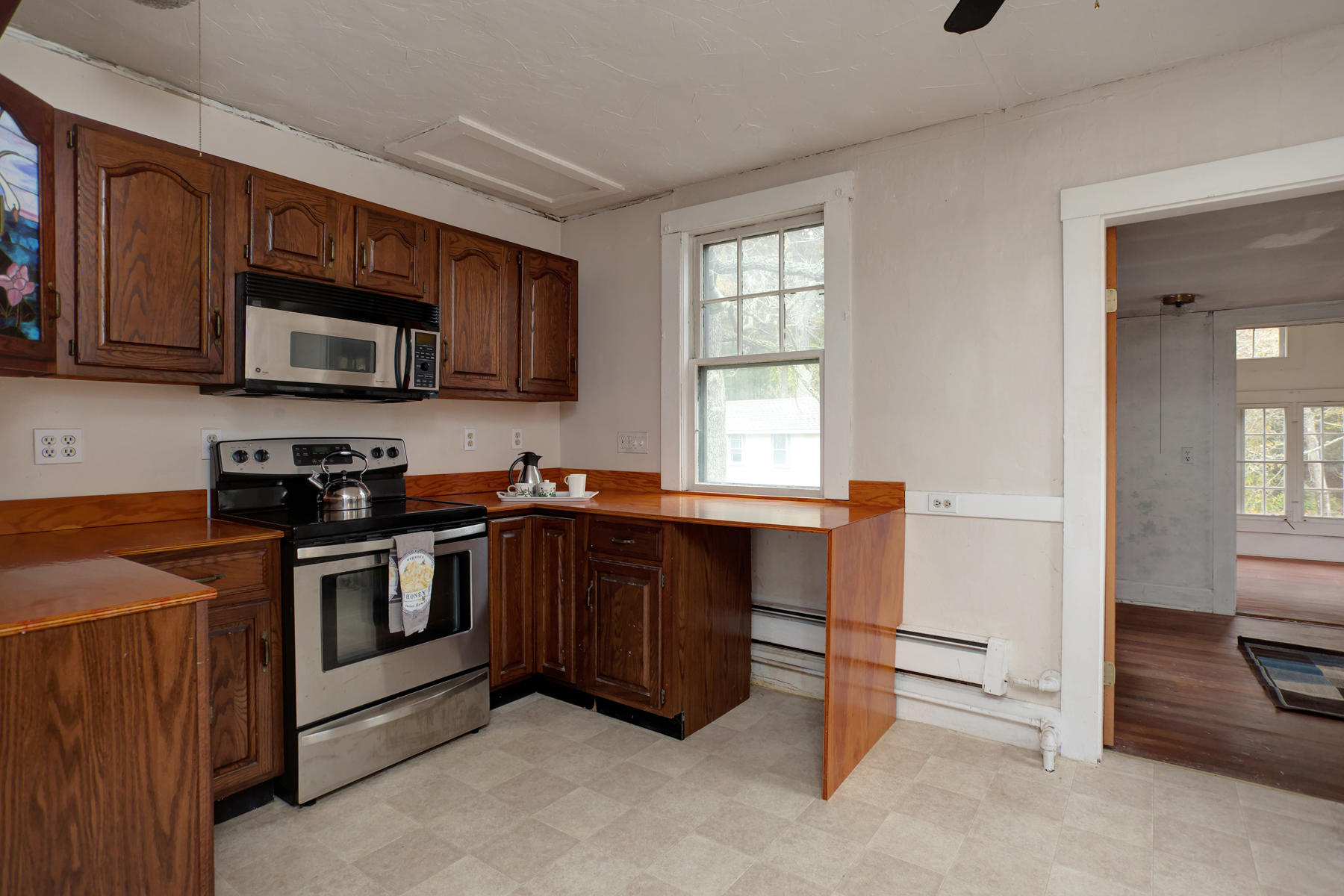 27 County Road Monument Beach, MA 02532 - Photo 10 of 17 a kitchen with stainless steel appliances granite countertop wooden cabinets a stove a microwave and a window