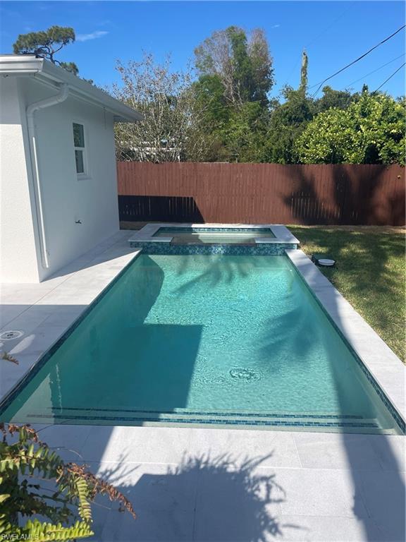 1175 9th Avenue North Naples, FL 34102 - Photo 30 of 33 View of pool featuring a pool with connected hot tub and a fenced backyard
