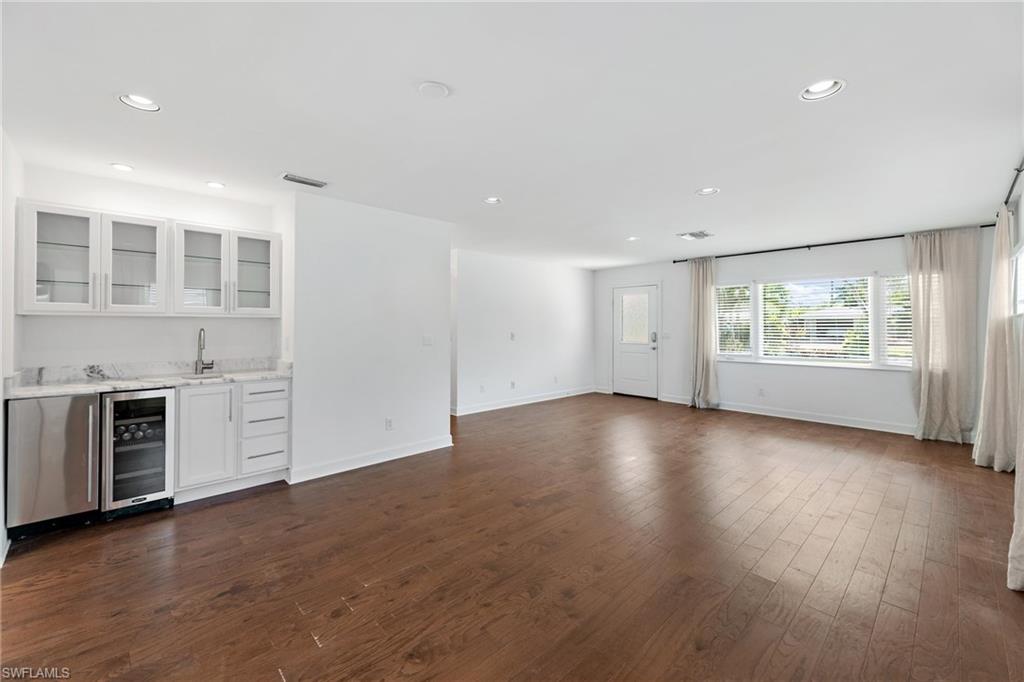 1175 9th Avenue North Naples, FL 34102 - Photo 6 of 33 Unfurnished living room featuring dark wood-type flooring, wet bar, and beverage cooler