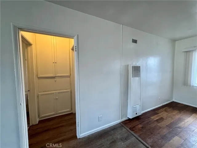 an empty room with wooden floor closet and windows