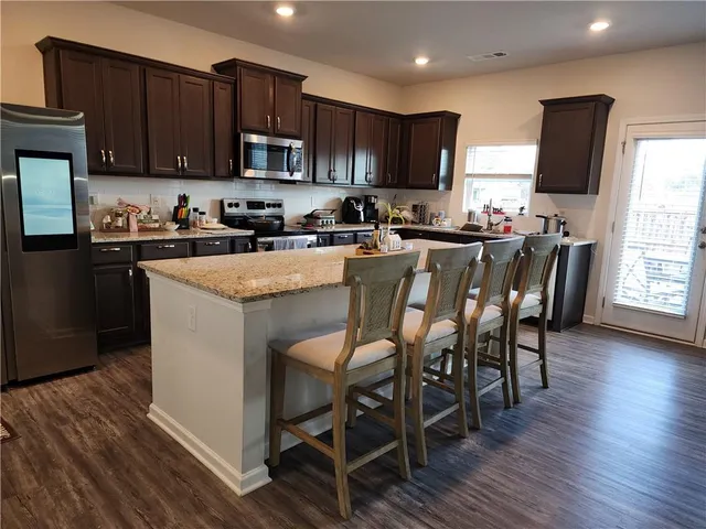 a kitchen with stainless steel appliances granite countertop wooden floors a stove top oven a sink and dishwasher