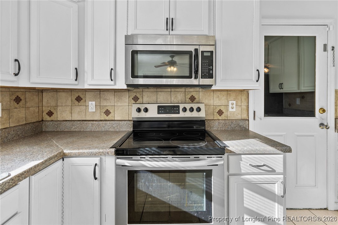 921 Flintwood Road Fayetteville, NC 28314 - Photo 17 of 44 a kitchen with stainless steel appliances granite countertop a stove a microwave and a white cabinets