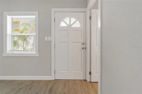 an empty room with wooden floor closet and windows