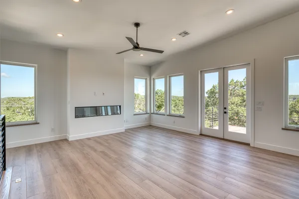 a view of an empty room with a window and wooden floor