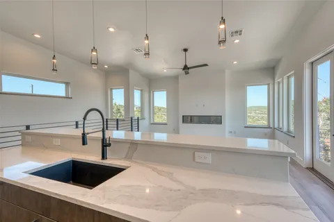 a large kitchen with granite countertop a large counter top a sink stainless steel appliances and cabinets