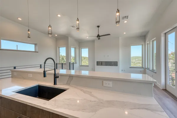 a large kitchen with granite countertop a large counter top a sink stainless steel appliances and cabinets