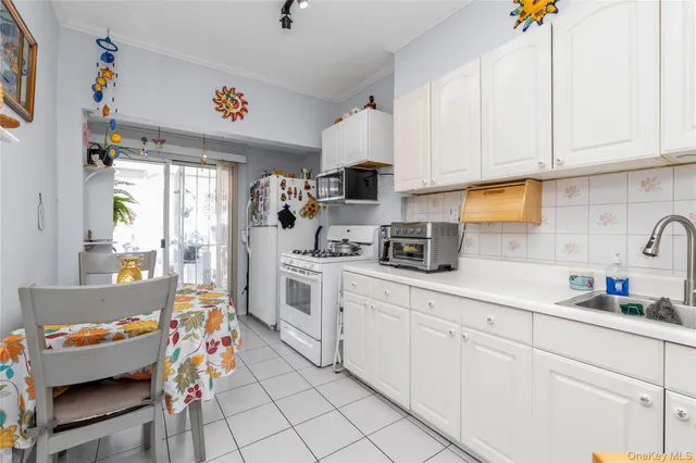 a kitchen with white cabinets and window