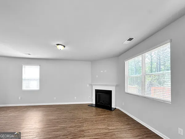 a view of empty room with wooden floor and fireplace