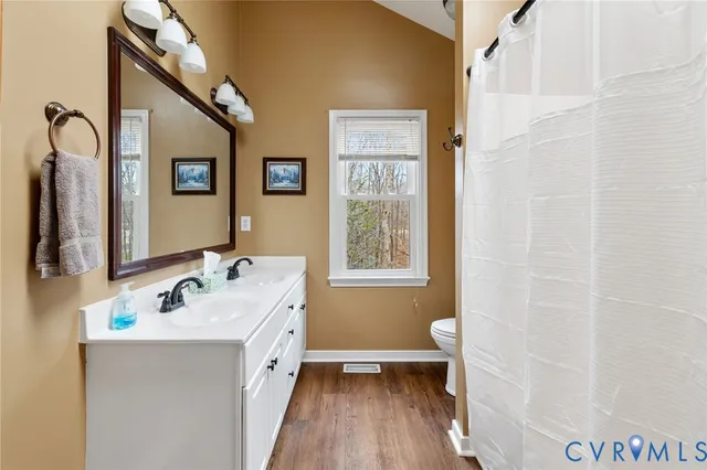 a spacious bathroom with a double vanity sink a toilet and a window