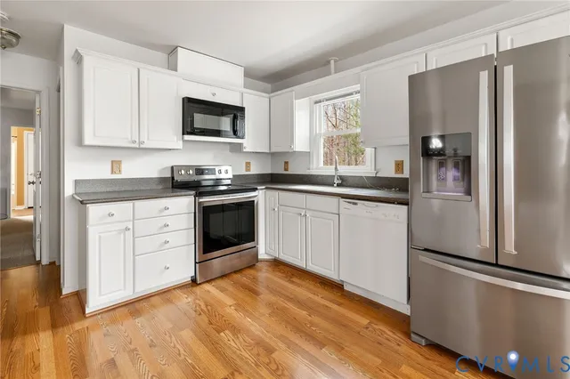 a kitchen with white cabinets stainless steel appliances and a window