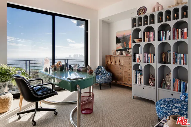 a view of living room filled with furniture and large windows