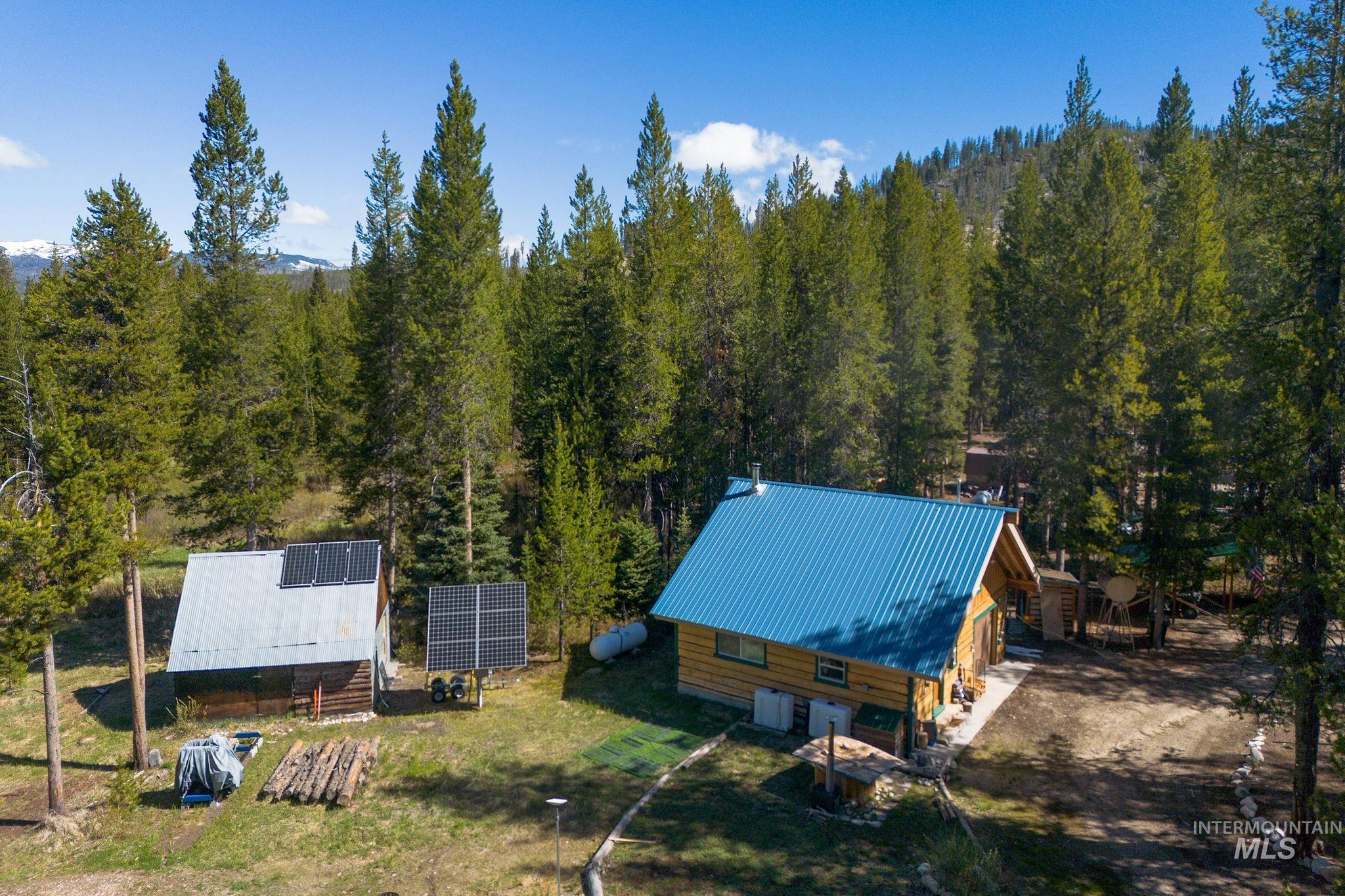 321 Secesh River Road McCall, ID 83638 - Photo 45 of 50 Log-sided cabin featuring a blue metal roof and surrounding evergreen trees