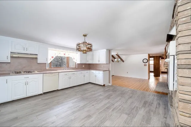 a large kitchen with cabinets wooden floor and stainless steel appliances