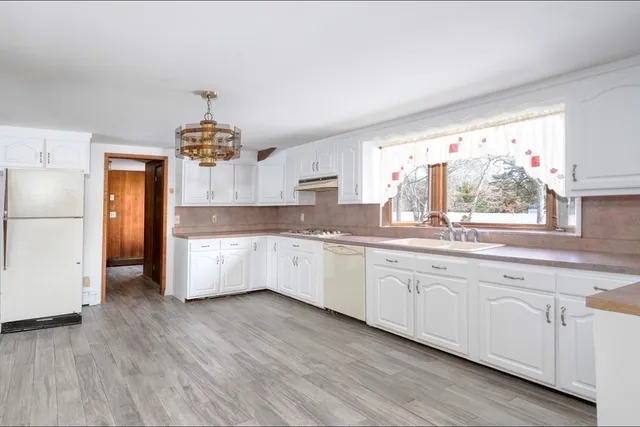 a large kitchen with stainless steel appliances a large counter top a sink and a window