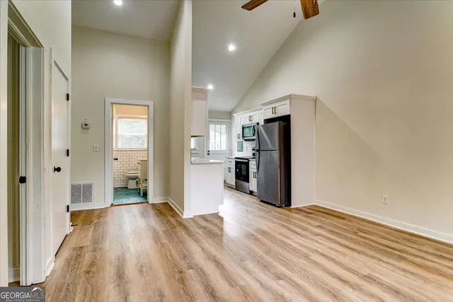 a view of a big room with wooden floor and a kitchen