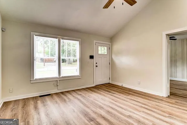 a view of an empty room with wooden floor and a window