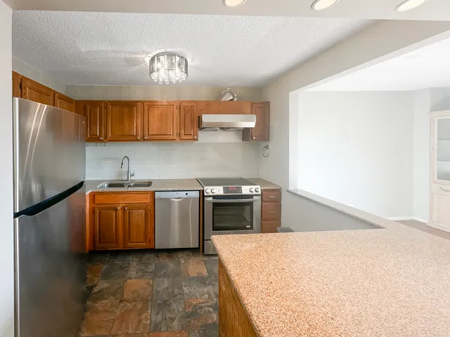 a kitchen with granite countertop a refrigerator a stove a sink and dishwasher