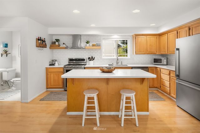 a kitchen with stainless steel appliances granite countertop a dining table chairs refrigerator and sink