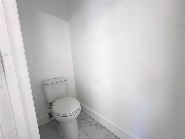 a white toilet sitting next to a white wall