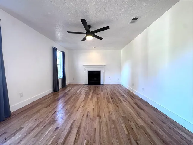 a view of empty room with wooden floor and fireplace