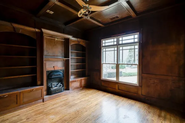 a view of an empty room with wooden floor and a window