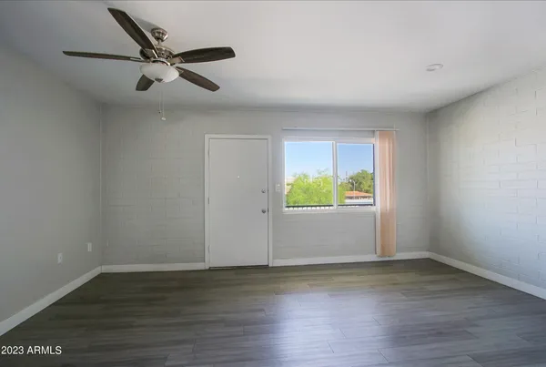 a view of an empty room with wooden floor and a window