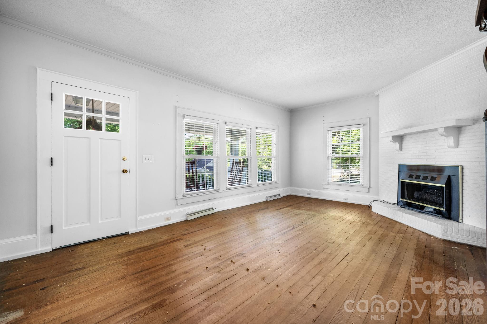 144 Hunter Bridge Road Stony Point, NC 28678 - Photo 16 of 45 an empty room with wooden floor fireplace and windows